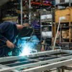 a young apprentice metal worker welding in factory