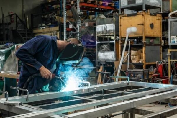 a young apprentice metal worker welding in factory